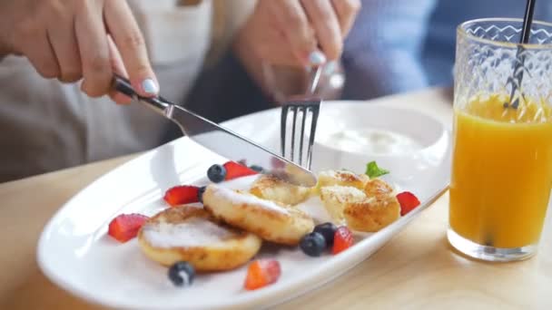 Flicka äter stuga cheescakes under frukost i kaféet — Stockvideo