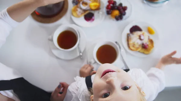 Вид сверху маленькой девочки пьет чай и смотрит вверх во время завтрака — стоковое фото