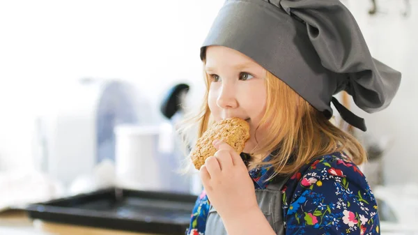 Маленькая девочка ест домашнее печенье с вареньем, приготовленным своими руками. — стоковое фото