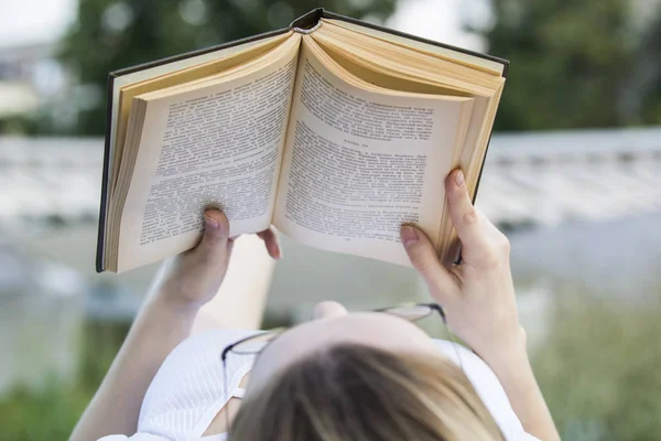 Jovem mulher lendo um livro velho deitado ao ar livre no dia de verão — Fotografia de Stock