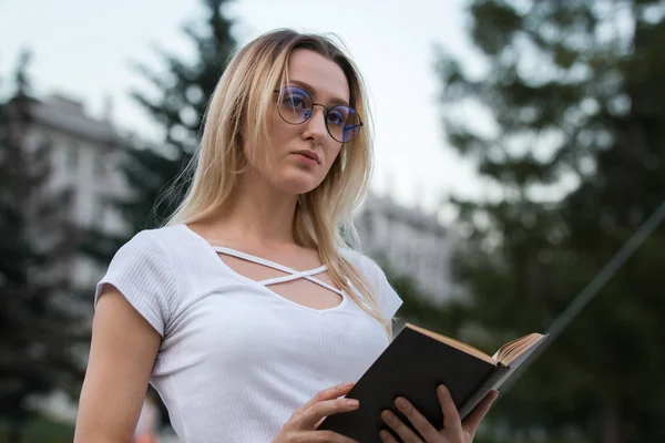 Retrato de uma menina pensativa com um livro em suas mãos ao ar livre — Fotografia de Stock