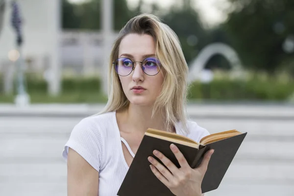 Retrato de uma jovem com um livro nas mãos desviando o olhar — Fotografia de Stock