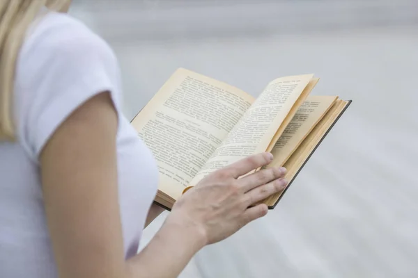 Jovem mão feminina segurando um livro velho - lendo ao ar livre — Fotografia de Stock