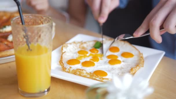 Αρσενικό χέρια κόβει ένα νόστιμο και χρήσιμο τηγανητά αυγά με ένα μαχαίρι και ένα δίκρανο στο εστιατόριο — Αρχείο Βίντεο