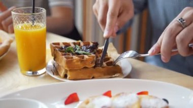 Erkek ellerini keser bir bıçak ve çatal restoranda nefis bir Belçikalı Waffle
