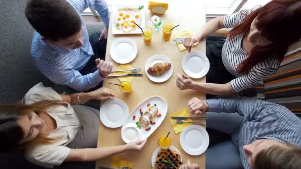 Ober wordt in de tabel een pizza op jonge vrienden genieten van een diner in restaurant — Stockvideo