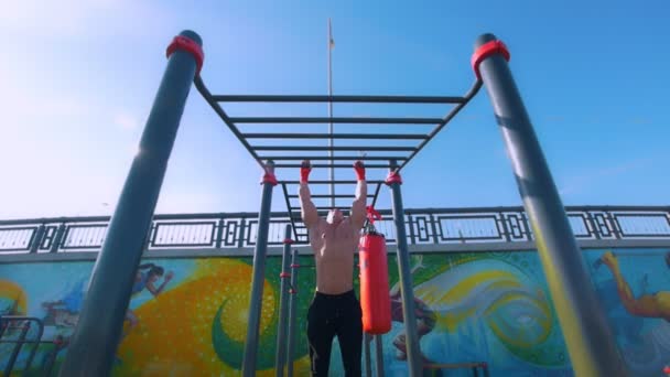 El hombre musculoso fuerte tiene entrenamiento en barras horizontales al aire libre — Vídeos de Stock