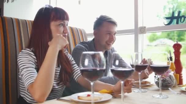 Amigos en el restaurante - joven hombre y mujer hablando y bebiendo vino — Vídeos de Stock