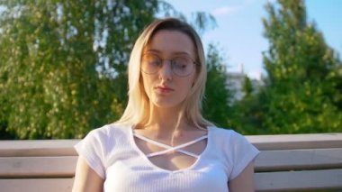 Gün batımında bankta kitap okuyan güzel genç bir kadın.