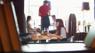 Genç çiftler öğle yemeği restoranda ve konuşurken, garson arka plan siparişinde kabul eder