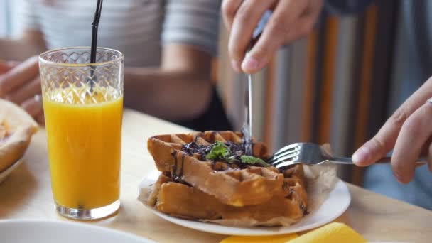 Мужские руки режут вкусные бельгийские вафли ножом и вилкой в ресторане — стоковое видео