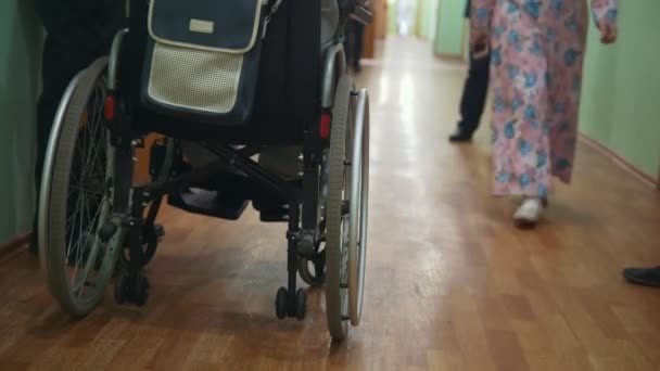 Uomo disabile su una sedia a rotelle in piedi all'interno dell'ospedale o dell'università — Video Stock