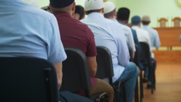 Pohled zezadu na muslimských mužů v jarmulek sedí u masového shromáždění — Stock video