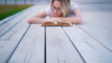 Genç kadın kentsel park açık havada yalan bir kitap okuma