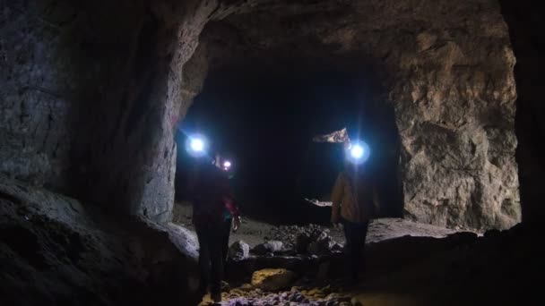 Niños en cascos con linternas exploran la cueva — Vídeos de Stock