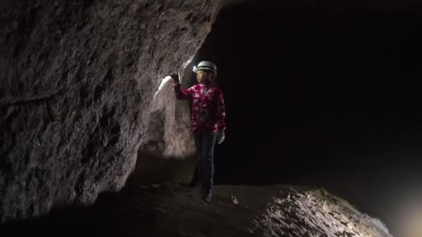 Menina com lanterna na mão examina os minerais na caverna — Vídeo de Stock