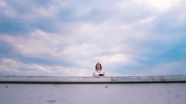 Chica bonita hipster con un libro contra el cielo azul se sienta a leer — Vídeos de Stock