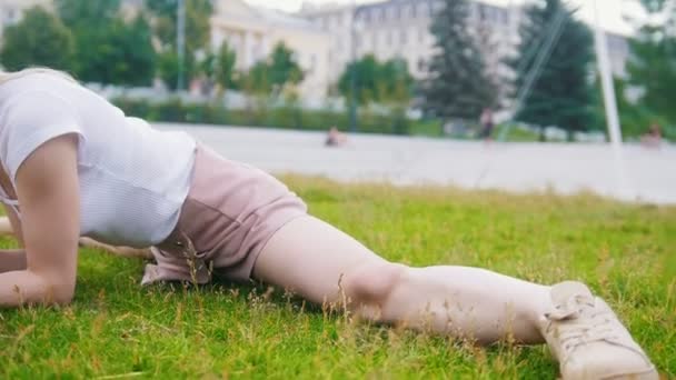 Junge Frau am Bindfaden, die im Gras liegt und ein Buch liest — Stockvideo