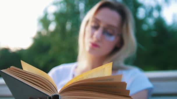 Gammal bok framför attraktiva flicka student läsning i parken — Stockvideo