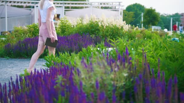 Attraktiv ung kvinna kom till trädgården med blommor och satte ner för att läsa en bok — Stockvideo