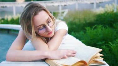 Çekici genç kadın kentsel bahçede bir kitap okuma yalan