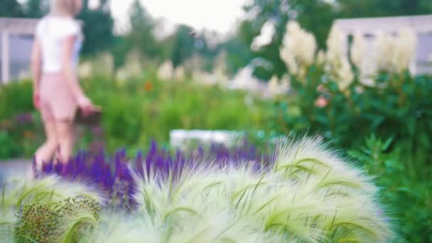 Jonge vrouw kwam naar de tuin om mooie bloemen zitten om een boek te lezen — Stockvideo