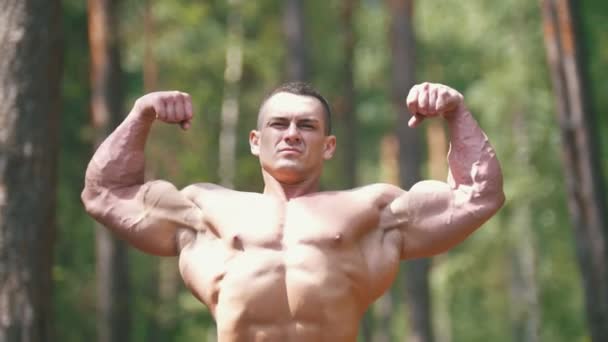 Opgeblazen mens trainingen in de zomer bos - enorme biceps — Stockvideo