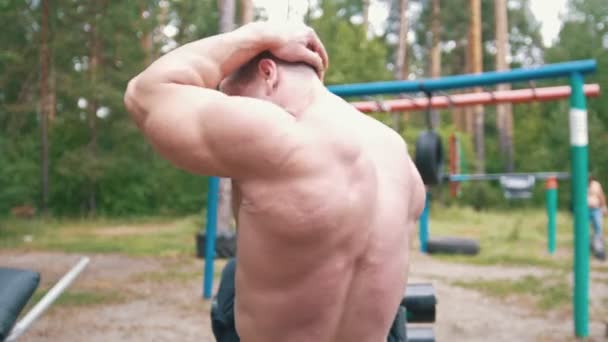 Bakifrån av muskulös man göra övningar för abs muskler på sport marken i skogen — Stockvideo