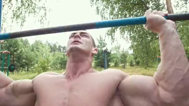 Gespierde man swingen met zware dwarsbalk in bos — Stockvideo
