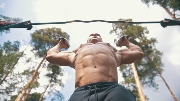 Muskulöser Mann Bodybuilder mit professionellen Sportgeräten im Wald beschäftigt — Stockvideo