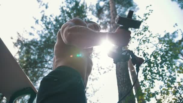 Sterke man bezig met zware handgemaakte halters in dennenbos — Stockvideo