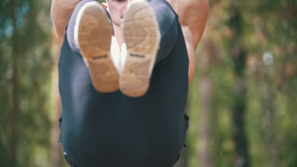 Stark man svänga för abs muskler på ribban i skogen — Stockvideo