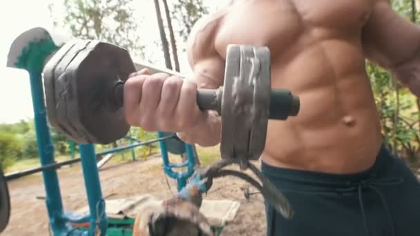 Ogromny mięśni ręki mężczyzna podnoszenia ciężkich żelaza hantle w parku sportowym na zewnątrz — Wideo stockowe