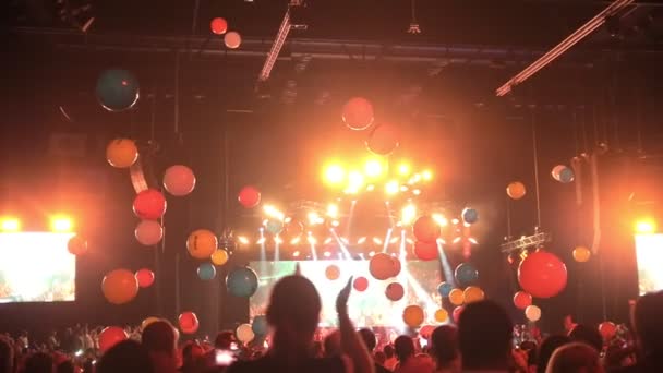 Une foule de gens s'amusent lors d'un concert avec des ballons volant autour de la salle de concert — Video