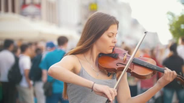 Молода скрипалька грає скрипку на пішохідній вулиці в літній день — стокове відео