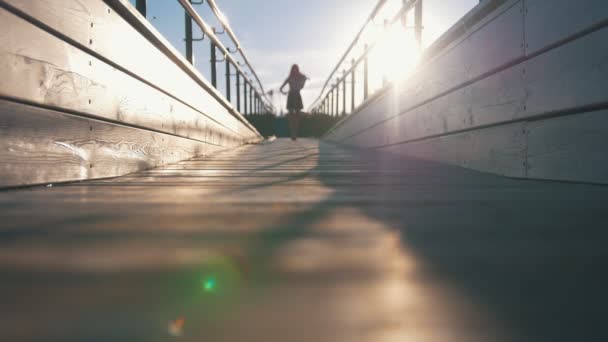 在日落时在天桥上行走的迷人女子的剪影 — 图库视频影像
