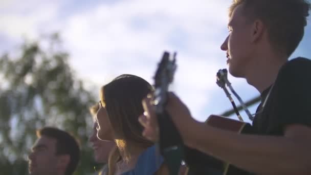 Biodrówki atrakcyjnych młodych przyjaciół, śpiewając piosenki z gitarą o summer zachód słońca na zewnątrz — Wideo stockowe