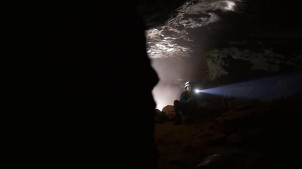 Kinder in Helmen mit Laternen erkunden die Höhle — Stockvideo