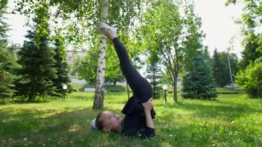 Küçük kız parkta yeşil çimenlerin üzerinde güneşli gün somersaulting