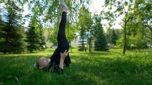 Hermosa niña haciendo ejercicios de gimnasia en la hierba en verano — Vídeo de stock