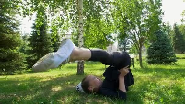 Liten flicka utför kullerbyttor på grönt gräs i parken på sommaren — Stockvideo