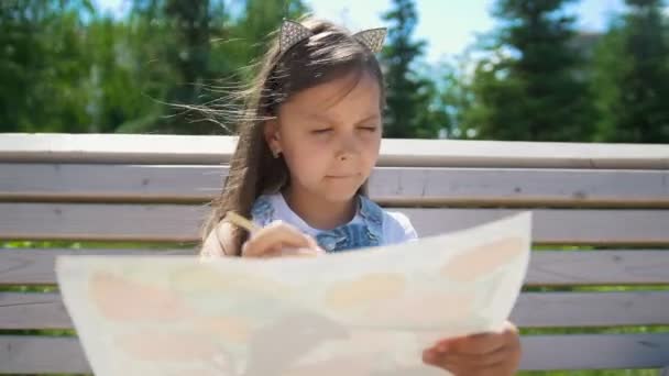 小女孩画家画了一个刷子坐在公园的长凳上 — 图库视频影像