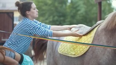 Genç kadın koyar bir eyer at üstünde açık havada yaz