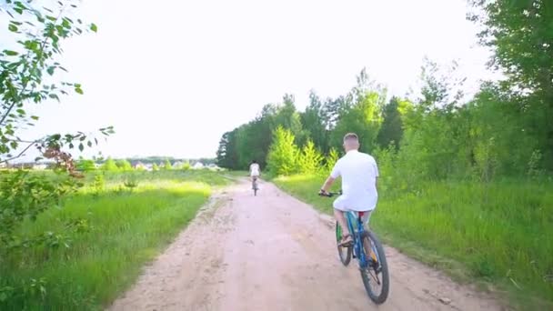 Jeune couple heureux à vélo sur le chemin dans le champ d'été — Video