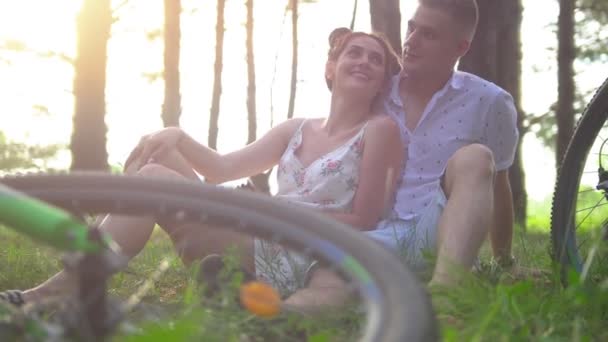 Ratten i en cykel som liggande på gräset framför glad älskande par har en vila efter cykling i sommar skog — Stockvideo