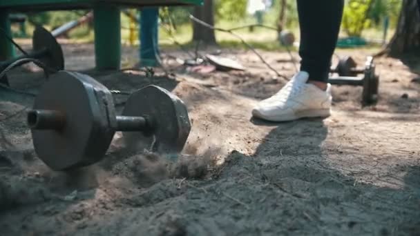Βαριά, σιδερένια αλτήρα πέφτει στην άμμο μπροστά στα πόδια του αθλητή σε λευκά αθλητικά παπούτσια — Αρχείο Βίντεο