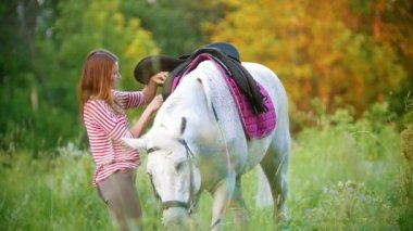 Genç kadın yaz alanında ata eyer giderir