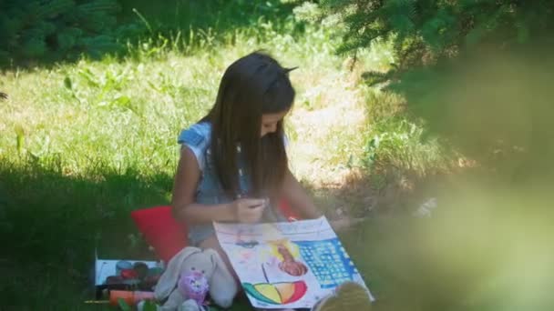 Menina feliz desenho tintas aquarela sentado na grama no dia ensolarado — Vídeo de Stock