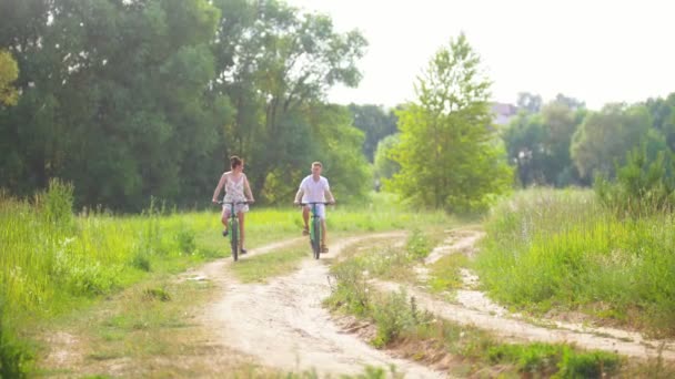 Pareja feliz en bicicleta en el camino en el bosque de pinos — Vídeo de stock