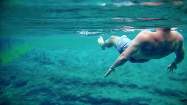 Молодой человек плавает под водой в озере — стоковое видео